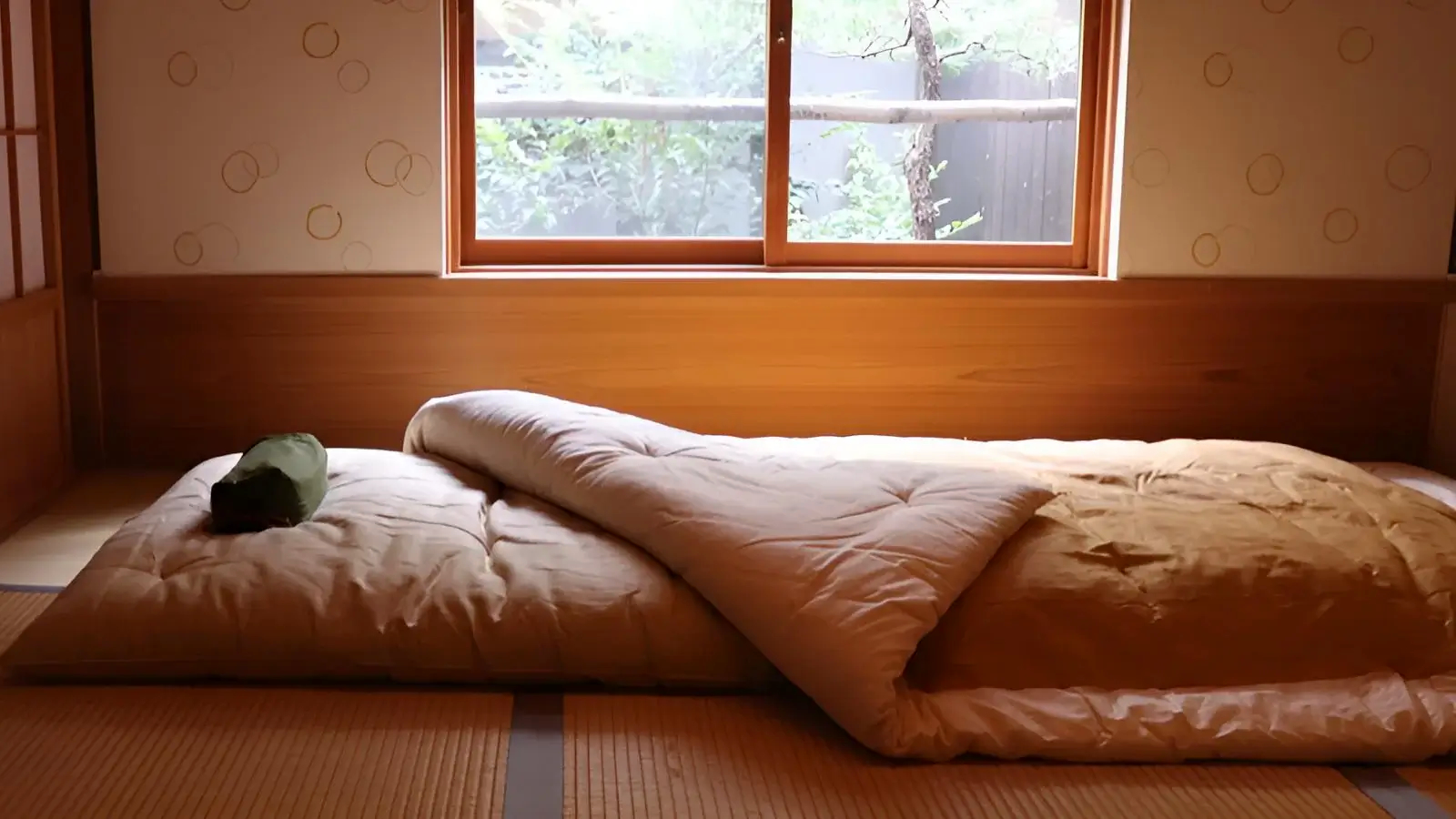 Véritable futon japonais posé sur des tatamis dans une pièce washitsu — source site officiel du fabricant Takaokaya