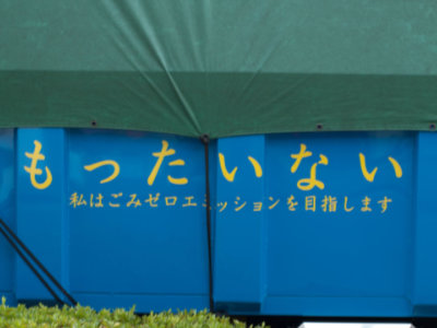 le terme mottainai + la phrase &ldquo;je m&rsquo;efforce d&rsquo;atteindre z&eacute;ro &eacute;mission&rdquo; &eacute;crit en japonais en jaune sur une benne bleue. - source wikip&eacute;dia, cr&eacute;dit photo Hajime Nagahata.