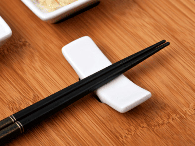 Paire de baguettes japonaises noires sur un repose baguettes appel&eacute; Hashioki pour &eacute;viter le watashi-bashi