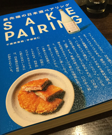 Couverture bleue du livre Saké pairing sur laquelle on retrouve des écritures japonaises blanches, ainsi qu’une assiette contenant un plat japonais et une bouteille de saké