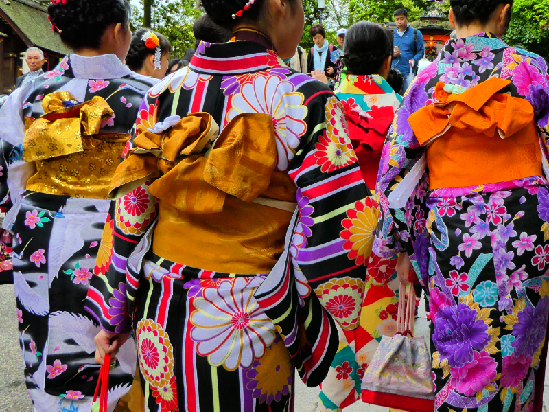 Japonaises de dos portant de magnifiques kimonos fleuris et colorés avec des ceintures obi de couleurs vives