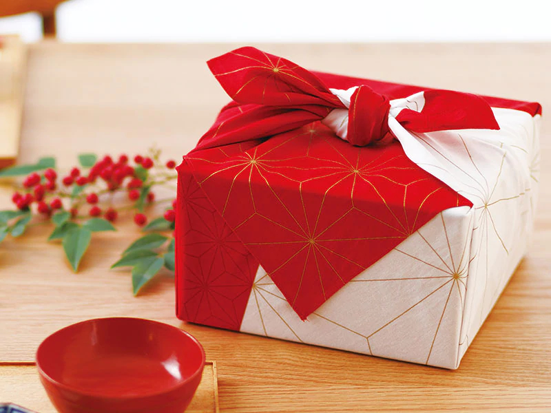 furoshiki rouge et blanc au motif asanoha dor&eacute; servant &agrave; l&rsquo;emballage d&rsquo;un cadeau - mise en avant du mottainai