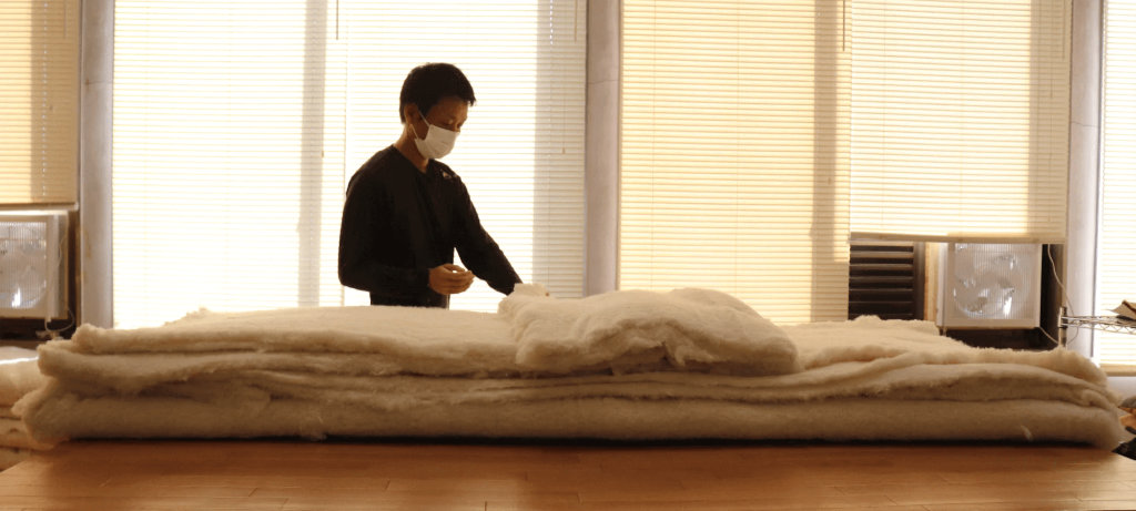 Fabrication du véritable futon japonais par superposition des couches de coton — source atelier takaokaya