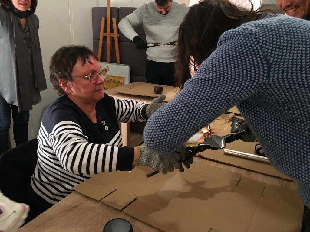 en plein pliage de sa feuille de cuivre pour réaliser sa grue d'origami