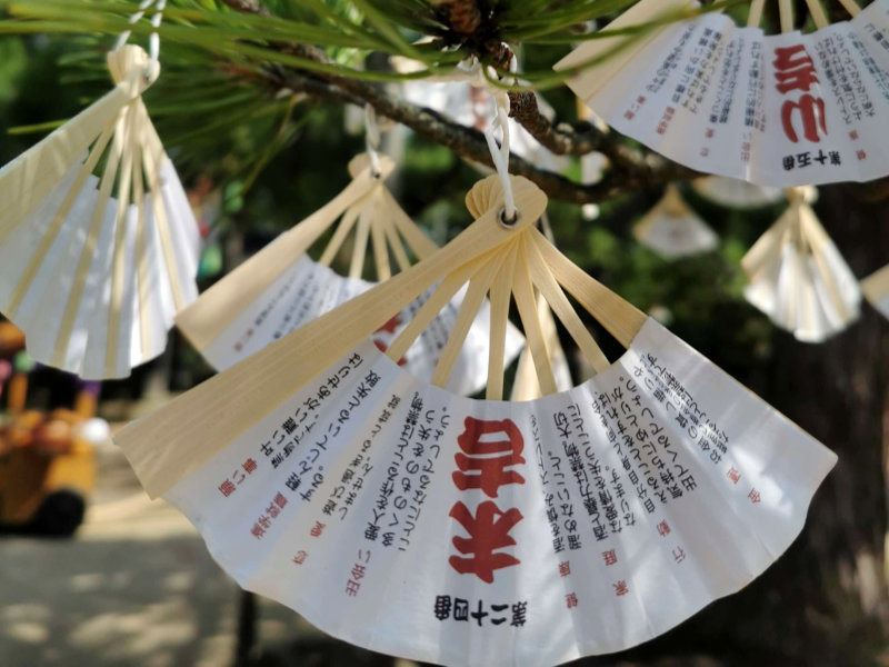 L’origine de l’éventail japonais : un symbole culturel et artisanal traditionnel - éventail sensu blanc avec des inscriptions suspendus comme porte-bonheur