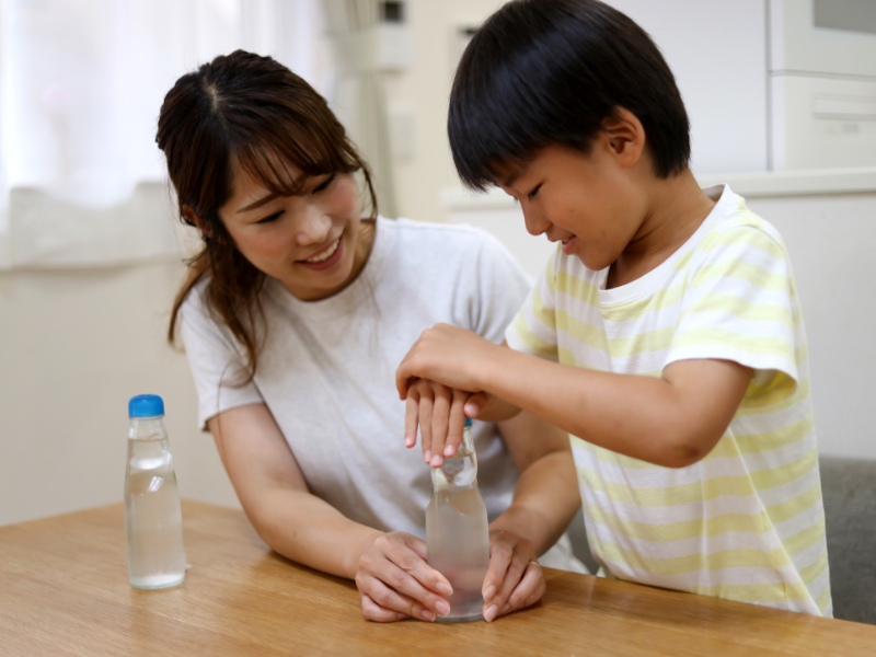 enfant japonais débouchant sa bouteille de ramune, la célèbre limonade japonaise, aidé par sa maman