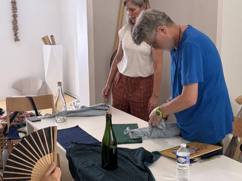 Participant à l'atelier furoshiki de Konjaku en pleine réalisation d'un emballage de bouteille.